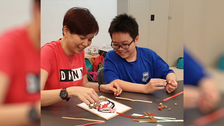 Mdm Soh Beng Mui, Principal of Juying Secondary School, is making artwork with a student.