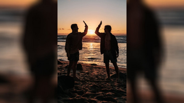 Silhouette of two men about to high five