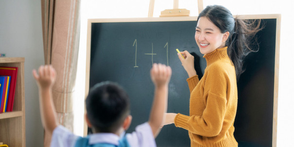 Asian woman teacher and her smart student in class room with backboard background