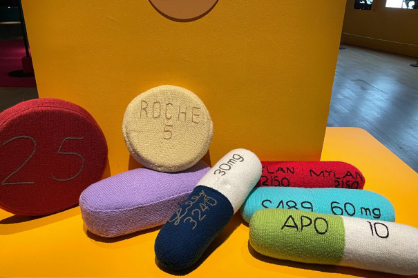Nearby, some cushions lay, knitted in the shape of pills and embroidered with names of common medications.