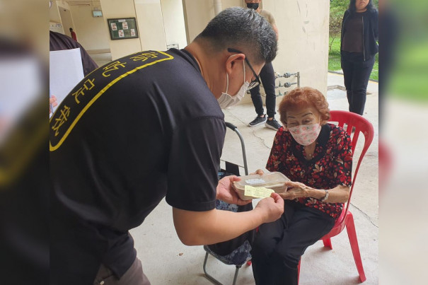 Steve giving out bento to elderly during a food distribution drive.