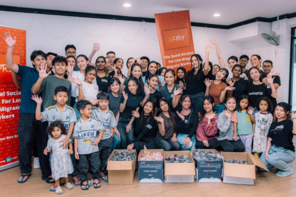 A volunteer group posing infront of boxes containing meals to be distributed to migrant workers