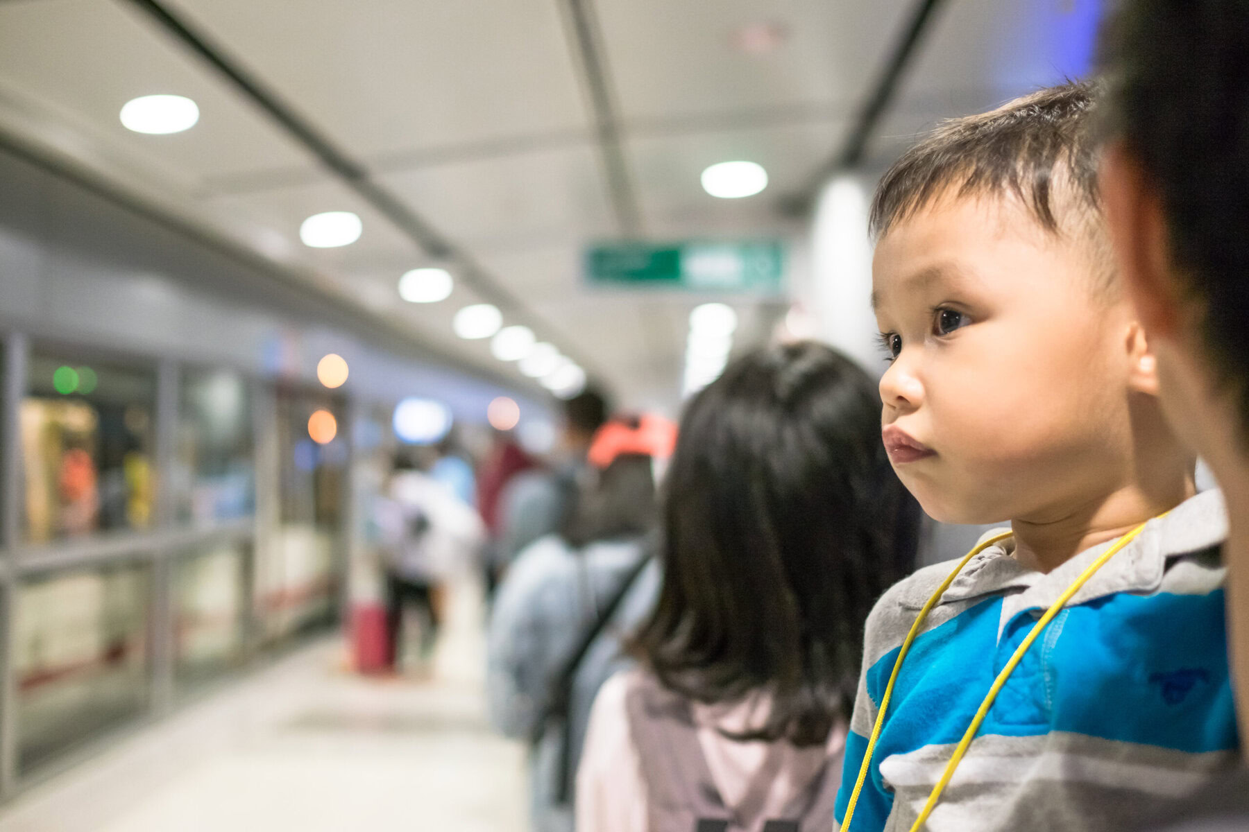 A young boy waiting in line at an airport, showcasing patience and kindness.