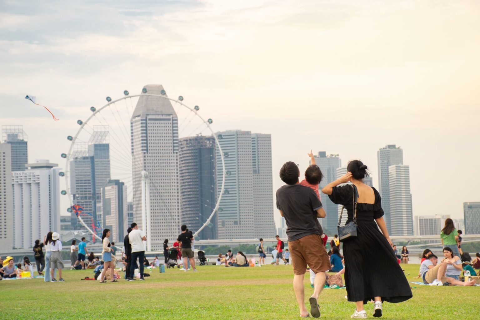 A colorful Pride flag displayed during a Singapore Pride event at Marina Bay, with the city skyline and a Ferris wheel in the background, promoting inclusivity and diversity.