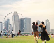 A colorful Pride flag displayed during a Singapore Pride event at Marina Bay, with the city skyline and a Ferris wheel in the background, promoting inclusivity and diversity.