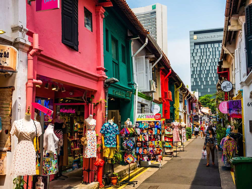 An outdoor scene of Haji Lane showcasing colorful shophouses and Pride-themed artwork celebrating diversity and kindness in Singapore.