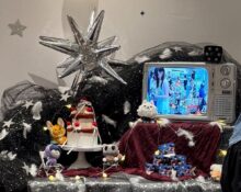 Decorative display featuring K-Pop themed gifts, plush toys, and a vintage TV showing a K-Pop scene, with star-shaped balloons and festive decorations.