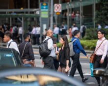 Crowd of diverse professionals crossing a busy street in Singapore, showcasing urban life and multiculturalism.