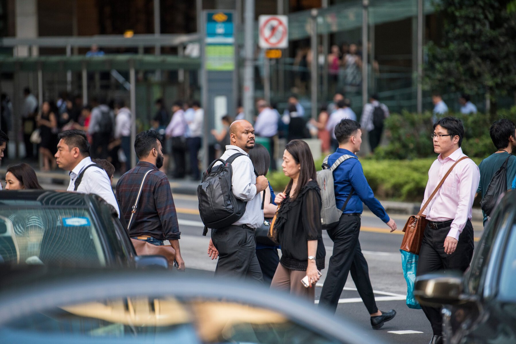 Crowd of diverse professionals crossing a busy street in Singapore, showcasing urban life and multiculturalism.