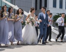 Happy wedding celebration with bride, groom, bridesmaids, and groomsmen outdoors in Singapore, showcasing diversity and joy.