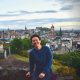 Smiling man enjoying view of Edinburgh skyline with historic buildings and cloudy sky, representing kindness, inclusion, and pride in diverse communities in Singapore.